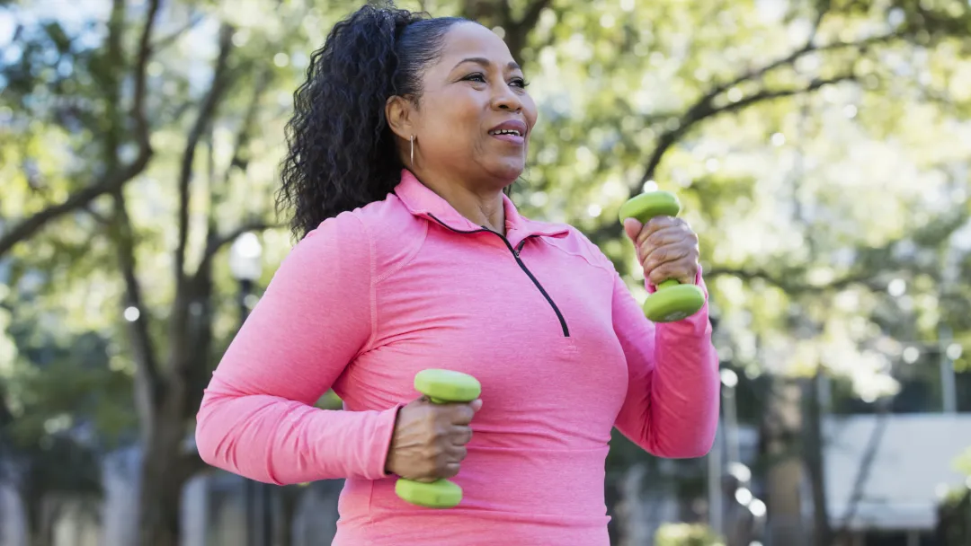 Woman walking outdoors and carrying small hand weights