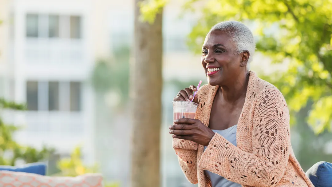 A Black Woman Enjoys a Smoothie on a Bench Outside