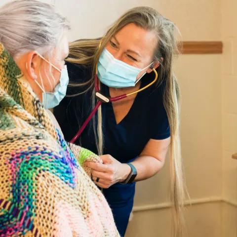 A caregiver comforts a patient as she uses her stethoscope