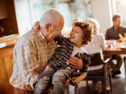 A grandfather holding his grandson on his lap.