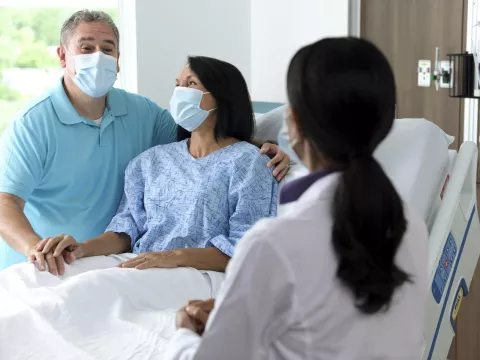 Couple in hospital room wearing masks talking to doctor