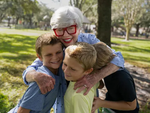 Woman hugging her grandchildren outdoors